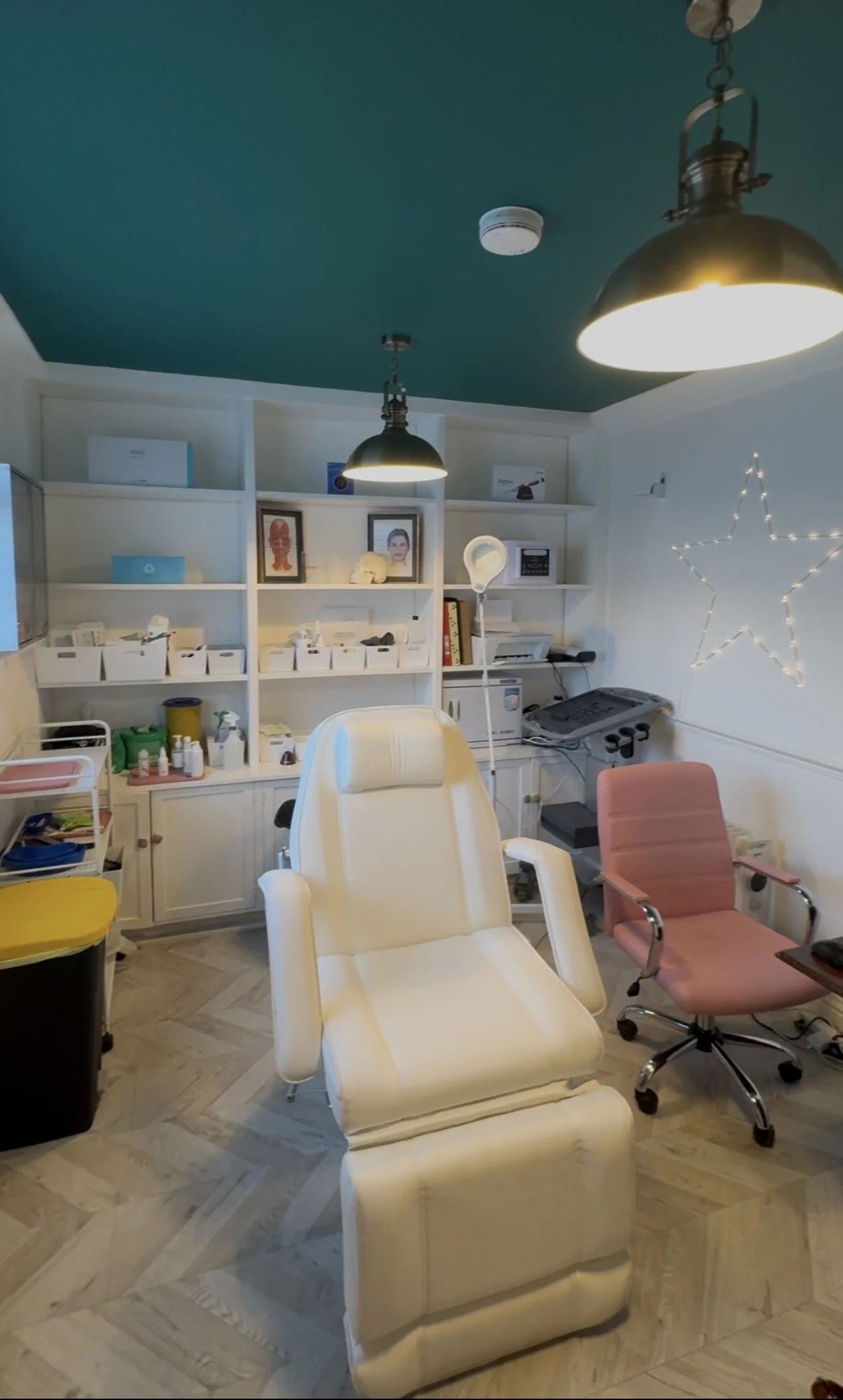 Treatment room at Happy Face Aesthetics with teal painted ceiling and brass pendant lights