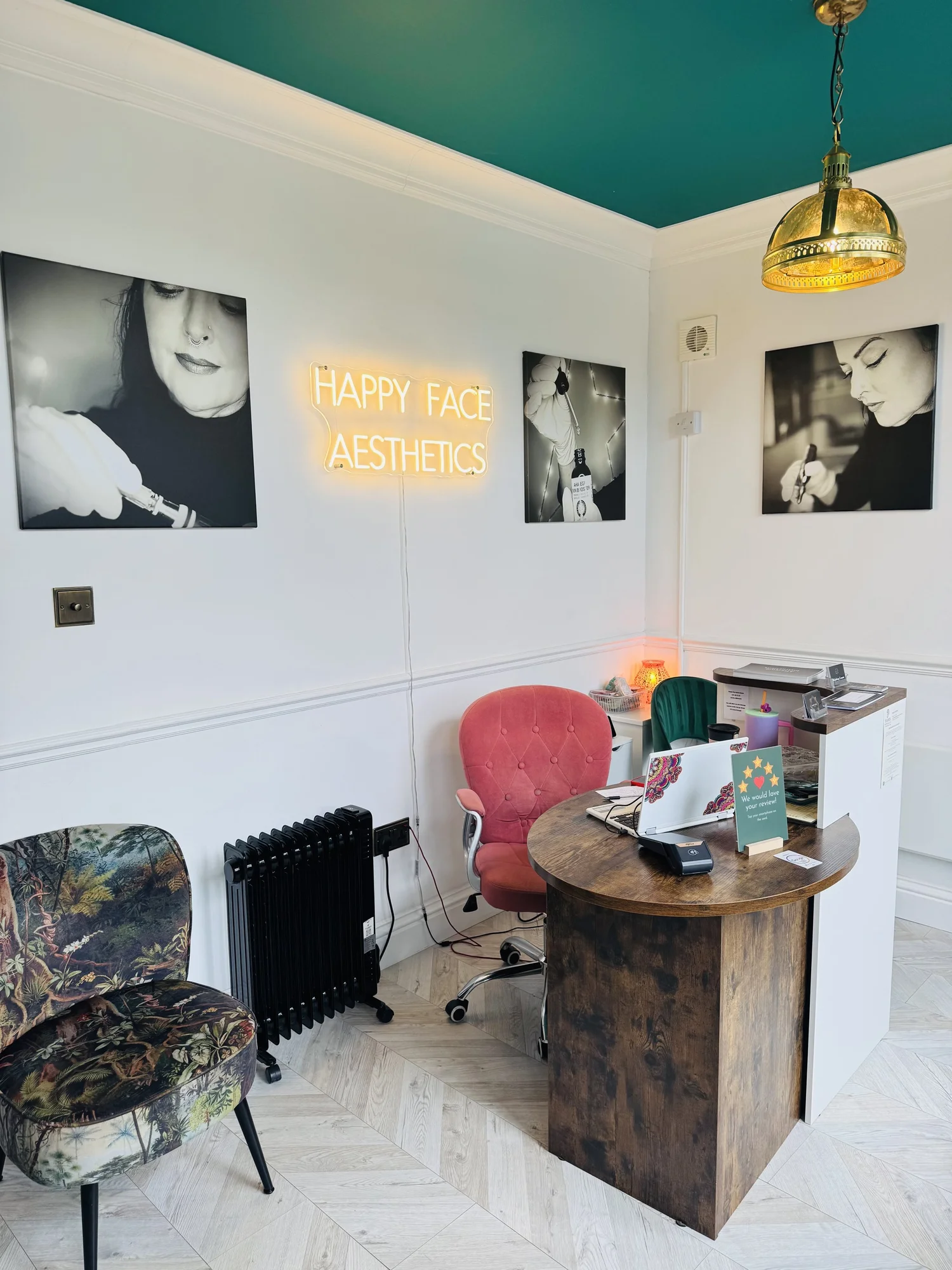 Happy Face Aesthetics clinic interior with teal ceiling, brass pendant light and glowing Happy Face neon sign