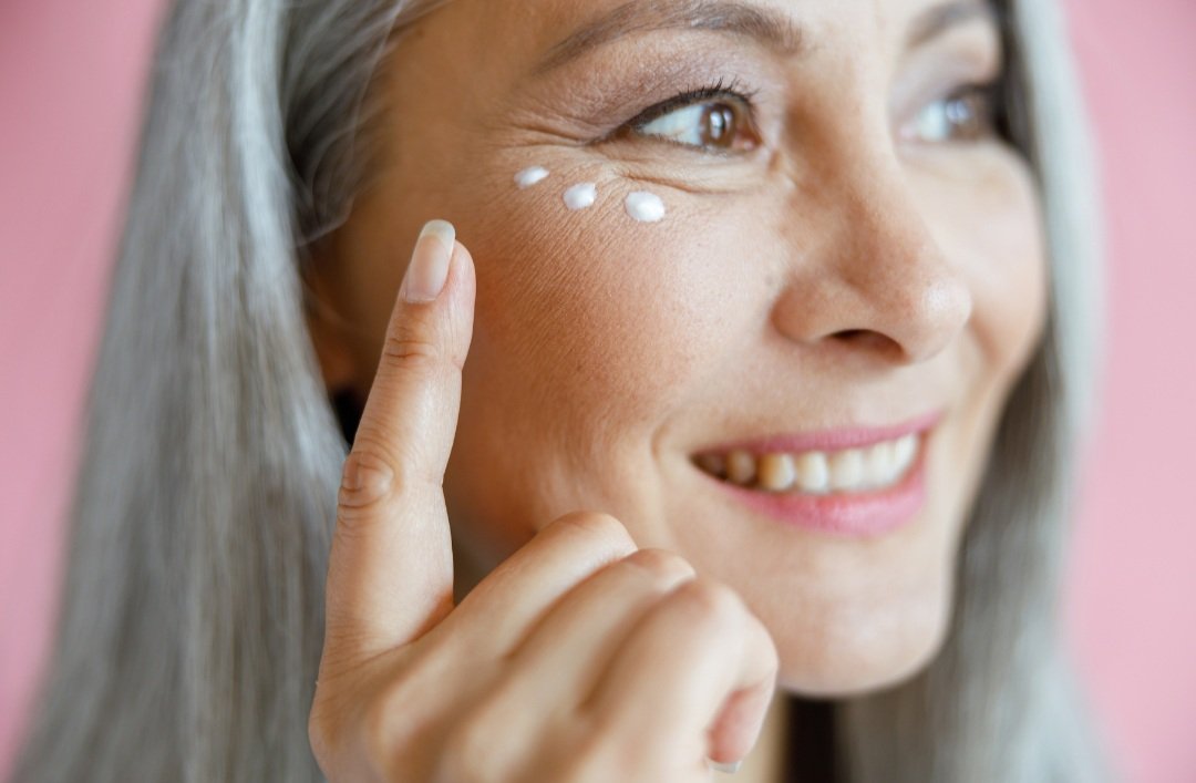 Woman applying skincare cream beneath her eye