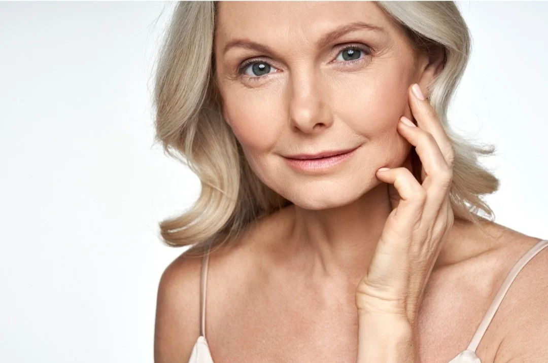 Smiling woman with healthy skin resting her hand against her cheek